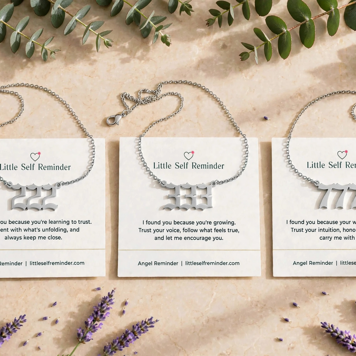 Three Silver-toned reminder bracelets displayed on white cards, arranged in a flat lay with eucalyptus leaves and lavender sprigs on a light beige background.